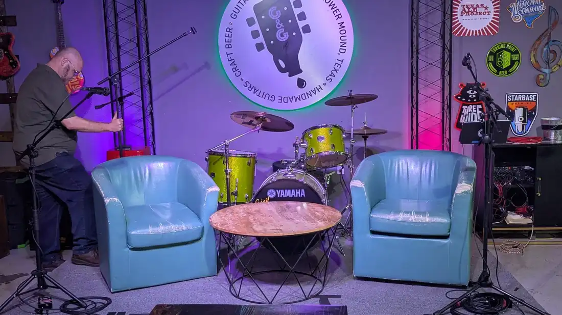 Two empty teal chairs facing each other on the stage at Guitars and Growlers before a show